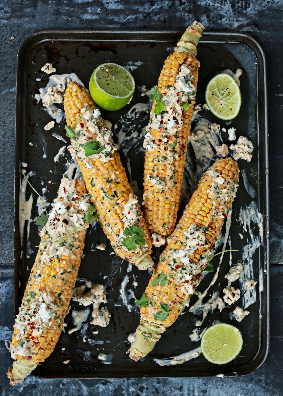 Corn on the cob with creamy topping, herbs, chili flakes and lime