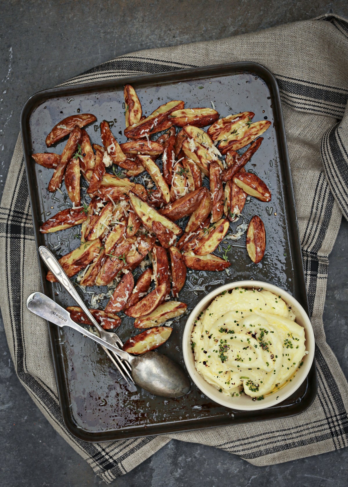 Roasted potato wedges with herbs and a bowl of mashed potatoes