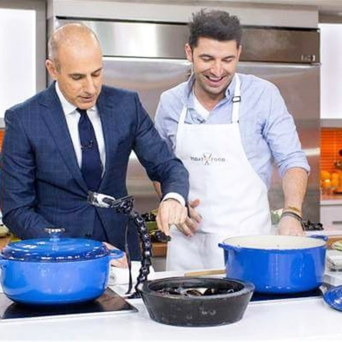 A cooking demonstration on a studio kitchen set with blue Dutch ovens.